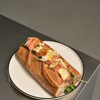 Close-up of a loaded focaccia sandwich with smoked salmon and cream cheese on a white plate